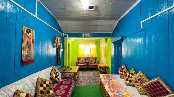 A relatively big room with confortable sofas, bed and wodden tibetan table of our Druk Home Stay